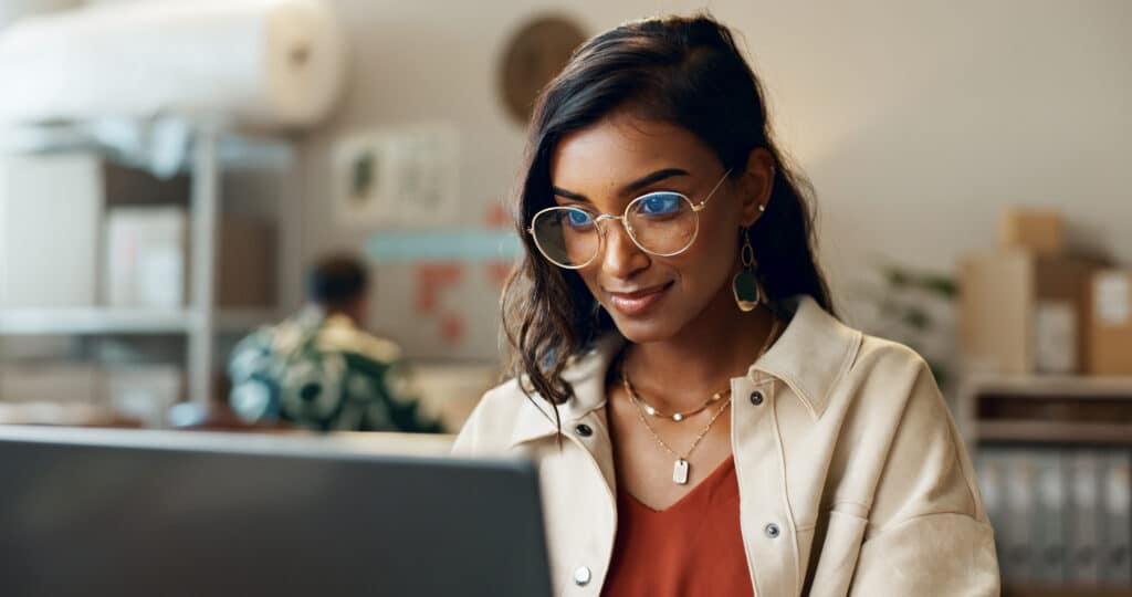 Woman, business and reading on laptop at work for research, feedback and supply chain for business. Indian, person and planning on pc for logistics, stock administration or package distribution data